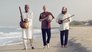blaye Cissoko à la kora, Kiya Tabassian au sétar et Patrick Graham aux percussions marchent ensemble sur une plage