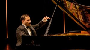 Le pianiste Jean-Philippe Sylvestre, en smoking, joue au piano Steinway sur scène