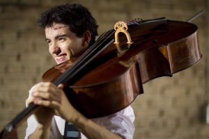A smiling Stéphane Tétreault, carrying a cello on his shoulder