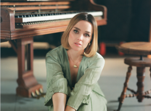 Viviane Audet sitting near a piano, wearing green